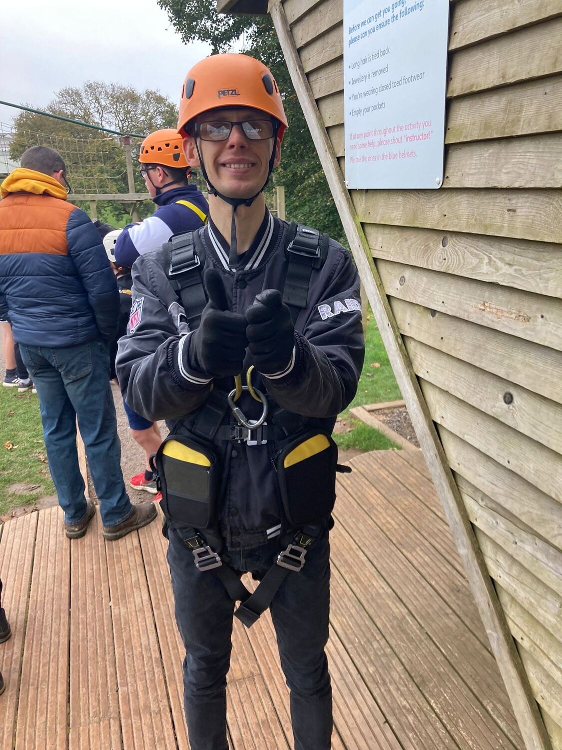Kitted out in a helmet and harness, giving a thumbs up before a climb